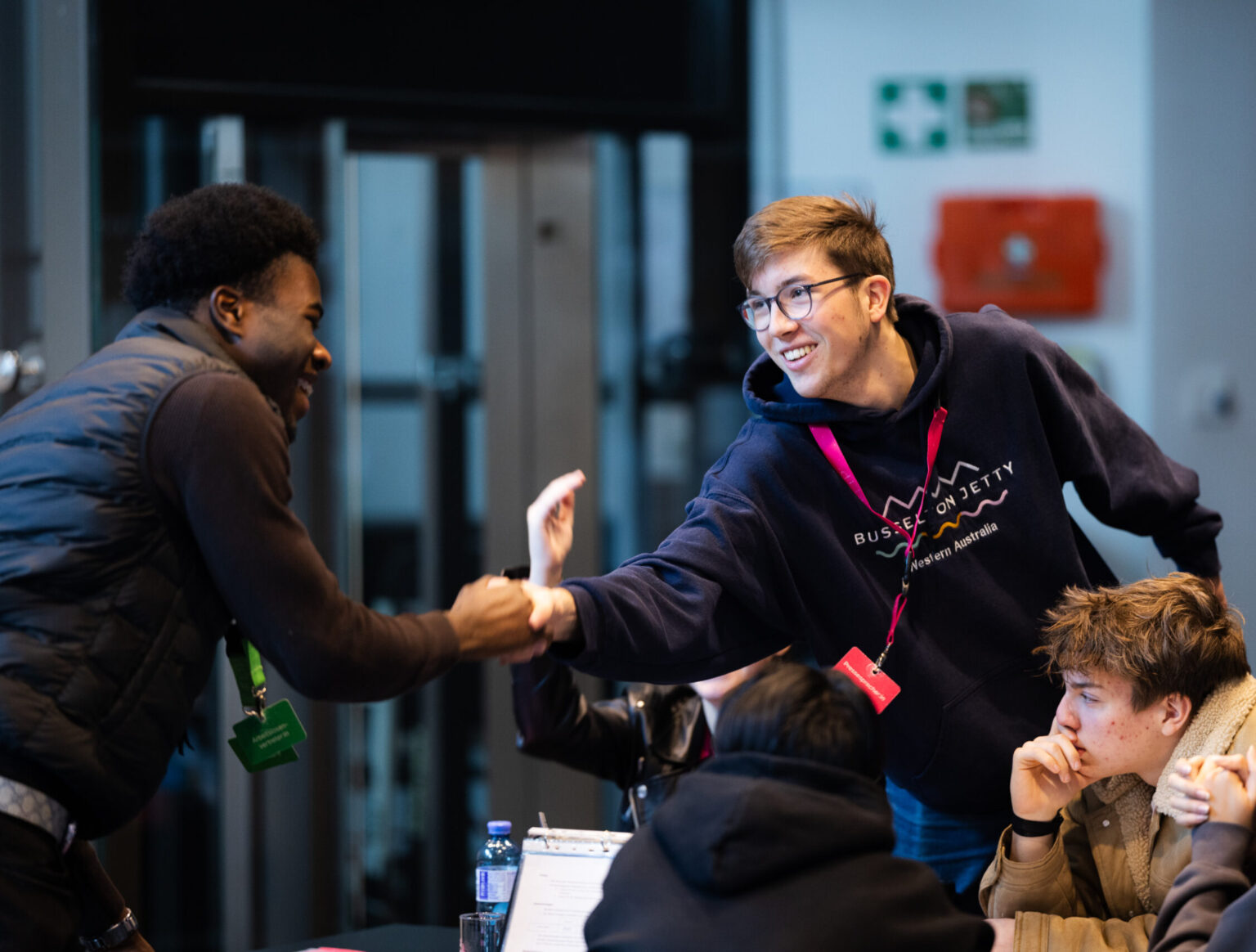 Zwei Schüler schütteln beim Planspiel ECOMANIA die Hände