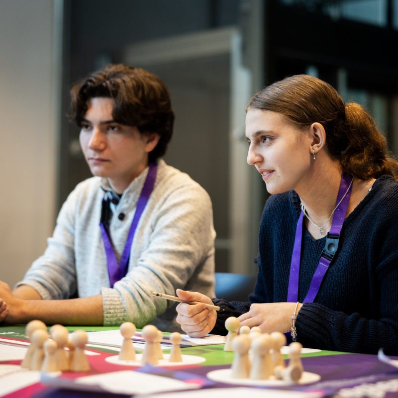 Eine Schülerin und ein Schüler spielen das Planspiel ECOMANIA